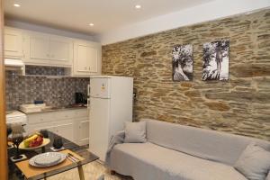 a kitchen with a couch in front of a stone wall at Chora's Stonehouse in Andros +12 photos