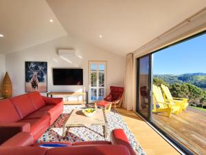 a living room with a red couch and a tv at The Barn Hot Water Beach in Hotwater Beach