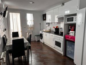 a kitchen with white cabinets and a table with chairs at Casa Vila in Riópar