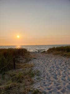 a beach with the sun setting over the ocean at charmantes Ferienhaus ruhig gelegen für 6 Personen in Welzin +29 photos