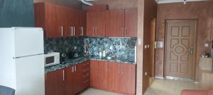 a kitchen with wooden cabinets and a white refrigerator at Апартамент 4-6 човека in Sveti Vlas