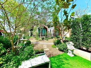 a garden with a bench and trees and a house at Plern-ura poolvilla cafe เพลินอุรา พูลวิลล่า คาเฟ่ in Ban Don Kha