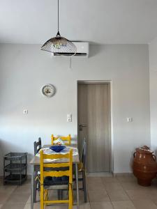 a dining room with a table and yellow chairs at Agnanti in AsfendhilÃ©s