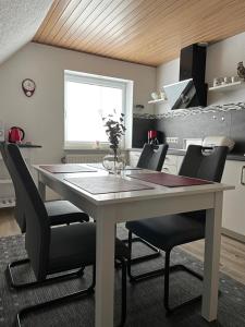a kitchen with a white table and black chairs at snevernheimat, Ferienwohnung in Schneverdingen