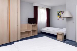ein Hotelzimmer mit einem Bett und einem Fernseher in der Unterkunft Hotel Meran Hallenbad & Sauna in Saarbrücken