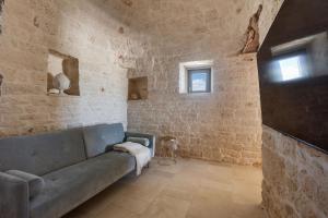 sala de estar con sofá azul en una pared de piedra en Brunaldi Trulli by Perle di Puglia, en Martina Franca