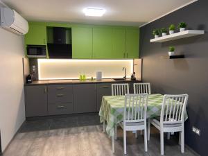 a kitchen with green cabinets and a table and chairs at Karát Apartmanok in Gyula