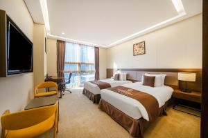仁川市Gloucester Hotel Incheon的有两张床和一台电视的酒店房间