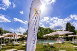 a surfboard sign in front of a pool with umbrellas at Club del Sole Viareggio Family Collection in Torre del Lago Puccini
