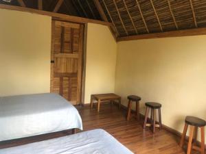 a bedroom with a bed and two stools and a door at Soanala in Moramanga +29 photos