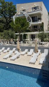 a group of lounge chairs and umbrellas next to a pool at Przno Apartment Most Oliva in Vrijesno