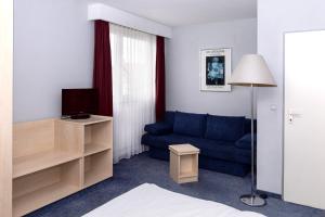 ein Wohnzimmer mit einem blauen Sofa und einem TV in der Unterkunft Hotel Meran Hallenbad & Sauna in Saarbrücken