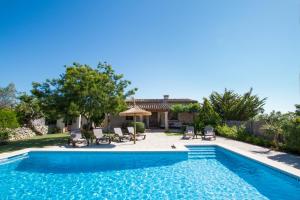 a swimming pool with chairs and a house at Can Daniel in Pollença