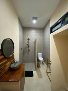 a bathroom with a sink and a mirror and a toilet at LM Home Mendira in Candidasa