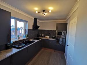 een keuken met zwarte kasten en een plafondventilator bij Abernethy Quay - Swansea Marina in Swansea