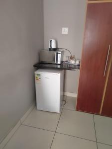 a small kitchen with a refrigerator and a microwave at La-Guna Guesthouse in Kuruman