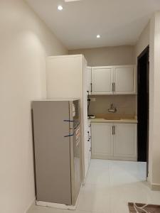 eine Küche mit weißen Schränken und einem Kühlschrank in der Unterkunft ملفى أبها in ‘Aryam