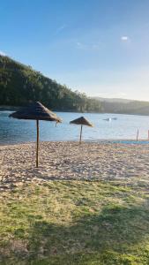 two umbrellas on a beach near the water at Riverlake House - frente ao lago e com jardim in Vila de Rei