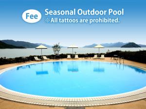 a large blue pool with chairs and umbrellas at Grand Prince Hotel Hiroshima in Hiroshima