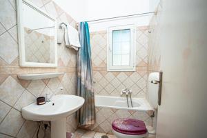 a bathroom with a sink and a tub and a toilet at THOLETO APARTMENTS in Agios Gordios