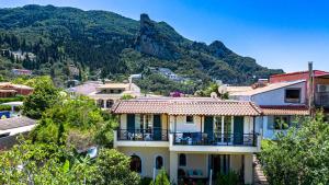a house with a balcony in front of a mountain at THOLETO APARTMENTS in Agios Gordios