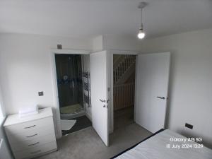Un dormitorio blanco con una cama y un baño. en Hornchurch House - Romford, en Harold Wood