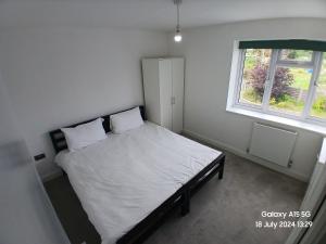 Un dormitorio con una cama con sábanas blancas y una ventana. en Hornchurch House - Romford, en Harold Wood 3 fotos más