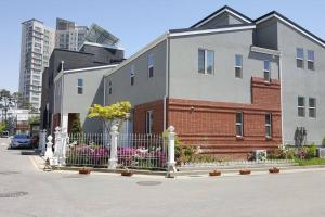 a building with a fence and flowers in front of it at All in one Guesthouse in Incheon