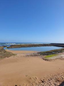 a beach with a pool of water in the ocean at Appartement à Bahia golf Beach Bouznika in Kasba Bou Hamira