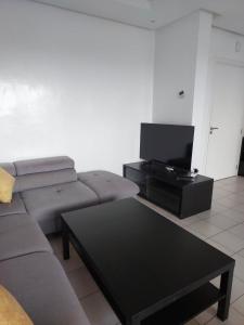 a living room with a couch and a flat screen tv at Appartement à Bahia golf Beach Bouznika in Kasba Bou Hamira