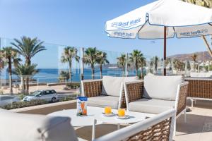 a patio with chairs and an umbrella and a table with drinks at Best Club Vacaciones Pueblo Indalo in Mojácar