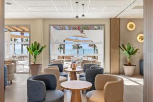 a waiting room with chairs and tables and a view of the ocean at Best Club Vacaciones Pueblo Indalo in Mojácar