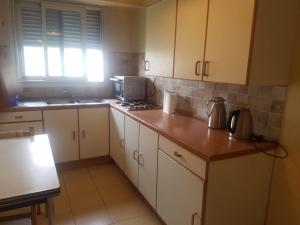 una cucina con mobili bianchi e un piano di lavoro di Studio Metro GALLIENI a Bagnolet