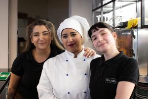 three women standing next to each other in a kitchen at Hotel Villabella in San Bonifacio