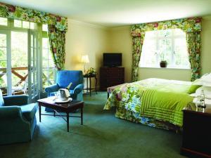 a bedroom with a bed and a chair and a television at Luton Hoo Hotel, Golf and Spa in Luton
