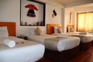 una camera con tre letti e un vestito appeso al muro di Fenix Hotel Machupicchu a Machu Picchu