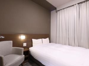 a hotel room with a bed and a chair at Dormy Inn Premium Shibuya-jingumae in Tokyo