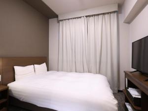 a bedroom with a white bed and a television at Dormy Inn Premium Shibuya-jingumae in Tokyo