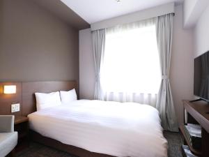 a hotel room with a bed and a window at Dormy Inn Premium Shibuya-jingumae in Tokyo