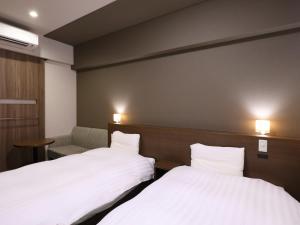 two beds in a hotel room with white sheets at Dormy Inn Premium Shibuya-jingumae in Tokyo