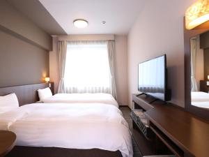 a hotel room with two beds and a flat screen tv at Dormy Inn Premium Shibuya-jingumae in Tokyo