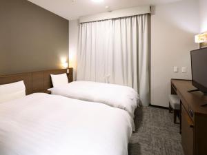 a hotel room with two beds and a television at Dormy Inn Premium Shibuya-jingumae in Tokyo