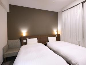 a bedroom with two beds and a chair in it at Dormy Inn Premium Shibuya-jingumae in Tokyo