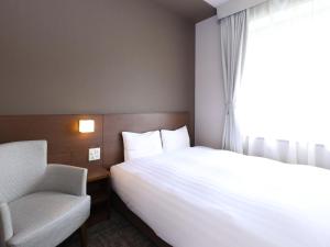 a bedroom with a bed and a chair and a window at Dormy Inn Premium Shibuya-jingumae in Tokyo