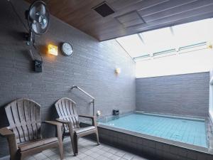 a bathroom with a tub with two chairs and a clock at Dormy Inn Premium Shibuya-jingumae in Tokyo