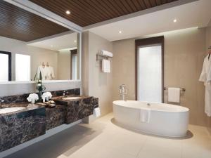 ein Badezimmer mit zwei Waschbecken und einer großen Badewanne in der Unterkunft Movenpick Resort & Spa Boracay in Boracay