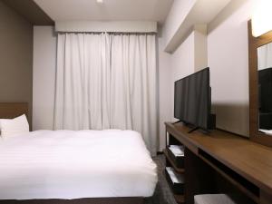 a bedroom with a bed and a flat screen tv at Dormy Inn Premium Shibuya-jingumae in Tokyo