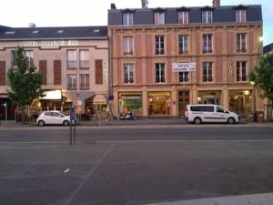a street with two cars parked in front of a building at Hotel Bar Restaurant Couleurs Sud in Charleville-M&eacute;zi&egrave;res