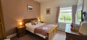 a bedroom with a bed with two lamps and a window at Halmer Grange Guest House in Goathland