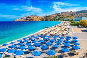 a beach with blue umbrellas and the ocean at Family Rhodes Villa 4 Bedrooms Villa Summer Memories Private Pool Lindos in vlicha